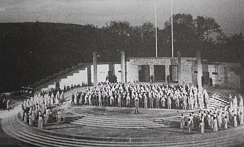 A vintage black-and-white photo of the Thingstätte Heidelberg on opening night, in 1935. It's a long shot, showing a large group of performers grouped around the stage.