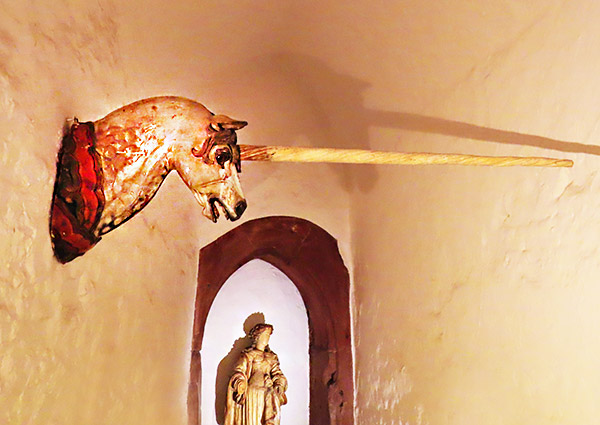 A "unicorn" on the wall of the museum. It is actually a carved wooden horsehead, similar to a carrousel horse, with a very long horn attached.